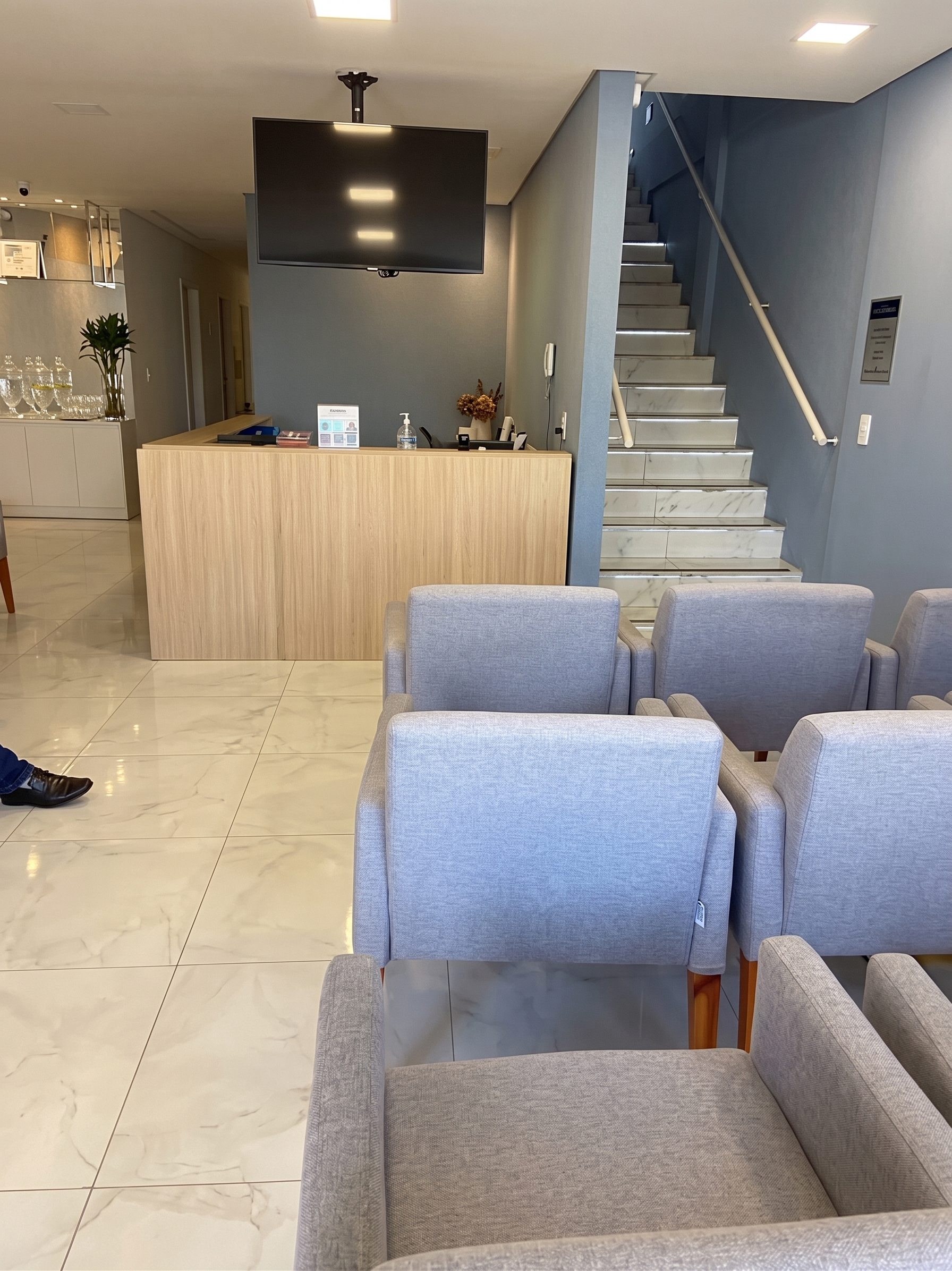 Recepção da ZASS Dental Clinic com balcão de atendimento e poltronas de espera